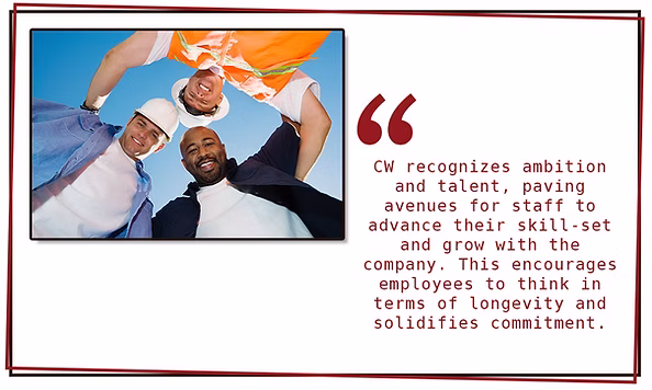 Three people wearing hard hats and safety gear stand in a circle, smiling and looking down at the camera. Beside them is a quote about CW Crates & Pallets supporting employee growth, longevity, commitment, and overall employee happiness.